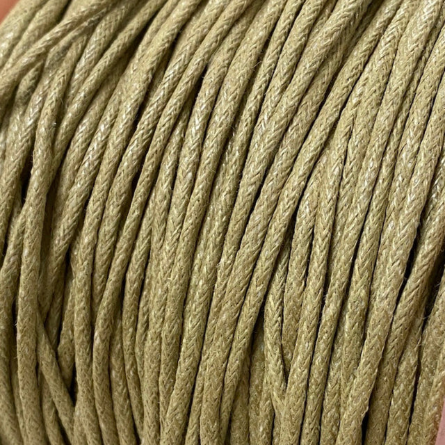 A spool of natural beige waxed cotton cord used for crafting and jewelry making.