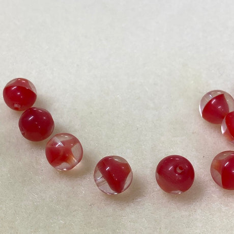 close up photo of a group of tomato red givre glass beads on a brown surface
